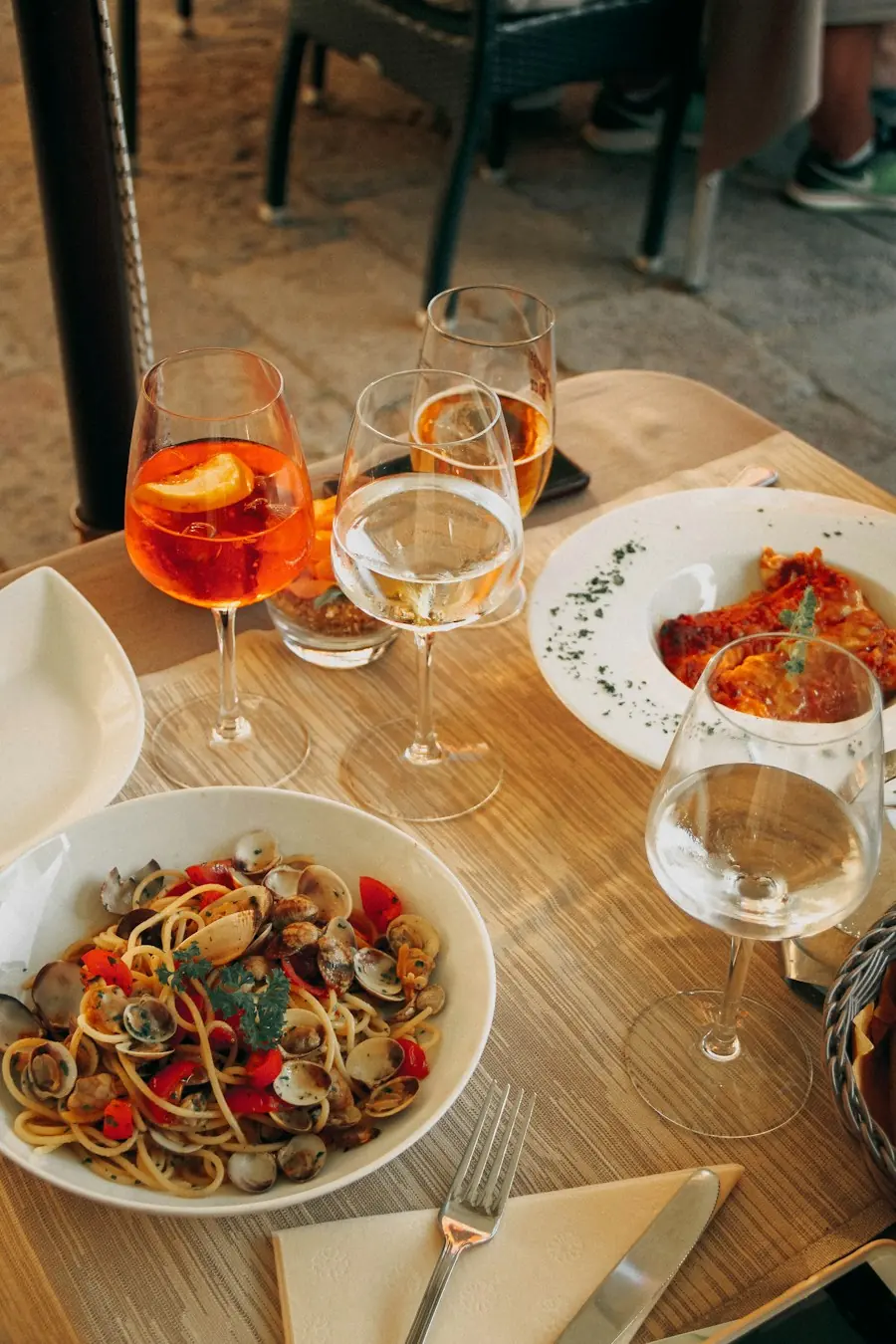 Tavola apparecchiata con calici di spritz e un piatto di spaghetti alle vongole
